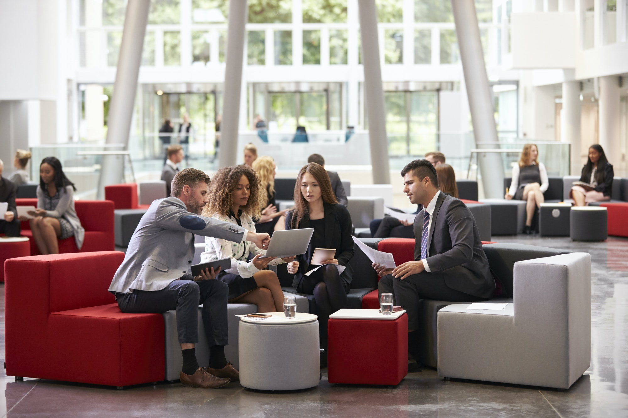 Businesspeople Meeting In Busy Lobby Of Modern Office