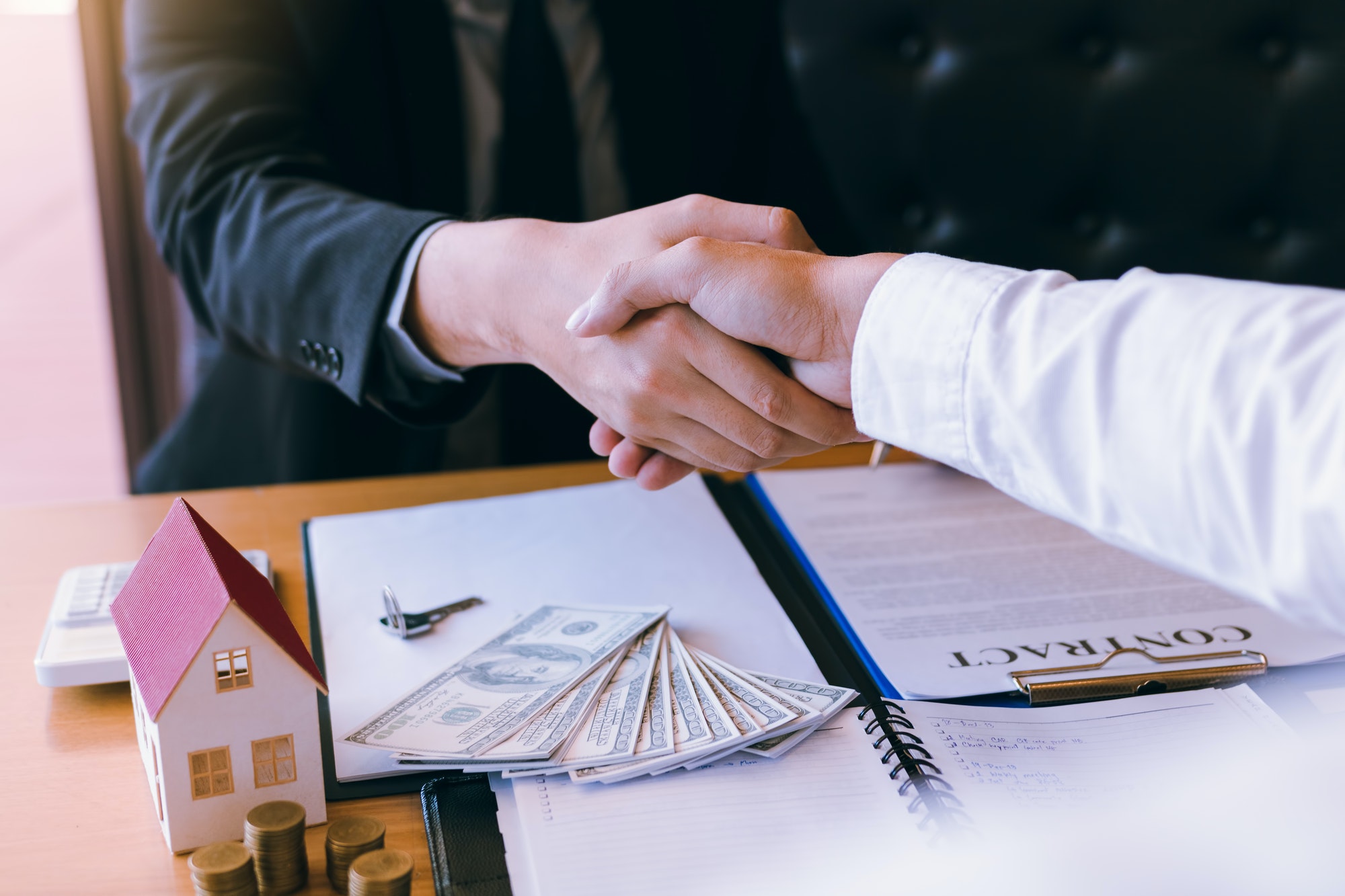 Home sales agents and buyers work on signing new homes and shaking hands.